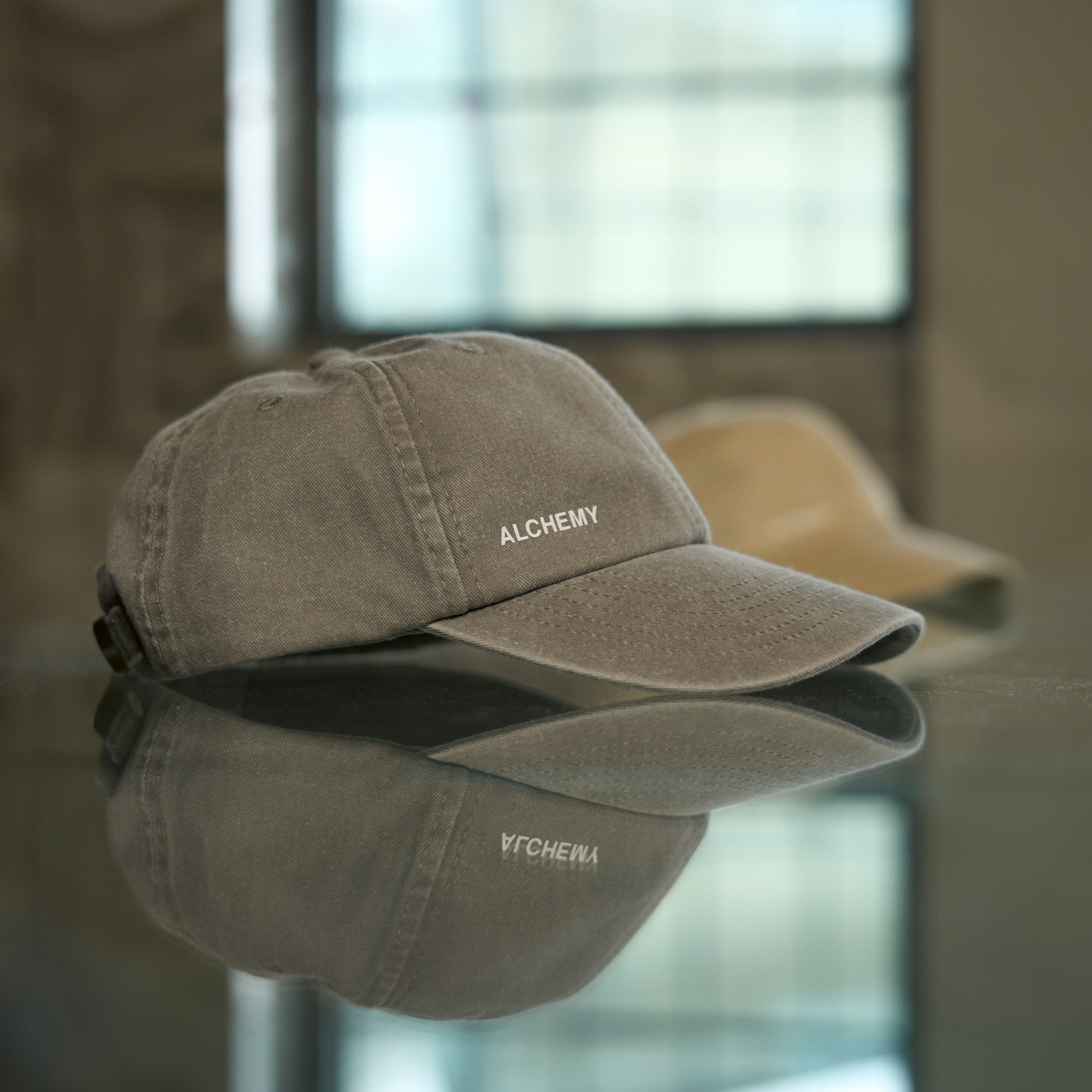 Gray cap with 'ALCHEMY' branding on a reflective surface