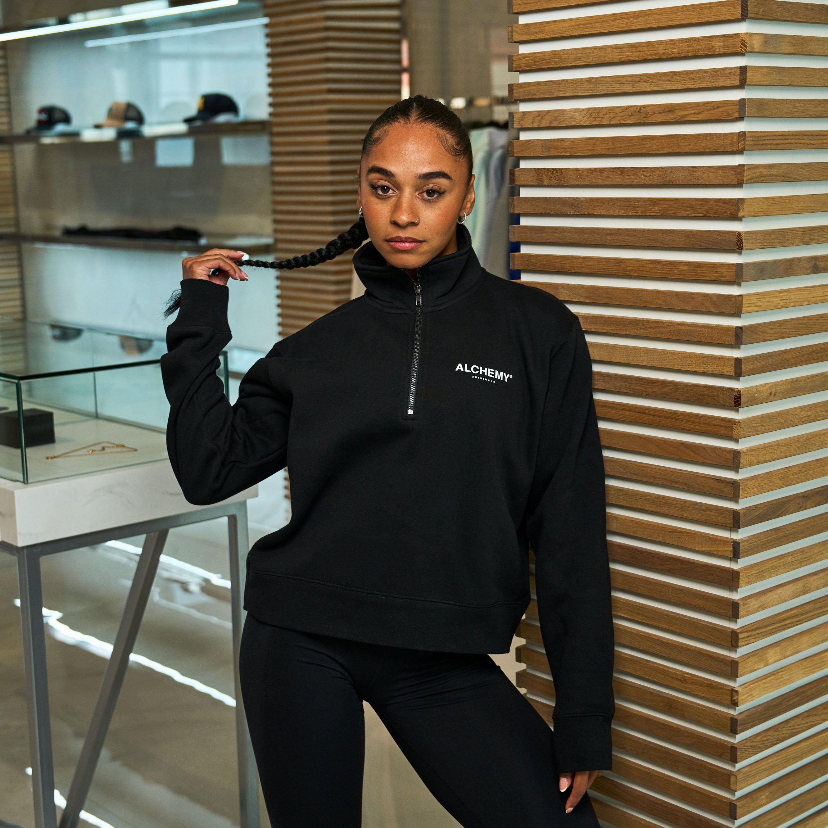 Tamika wearing Alchemy Orinigals Black Half Zip in an indoor setting